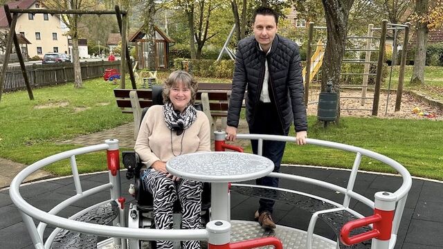 Eine Frau im Rollstuhl und ein Mann sind in einem barrierefreien Karussell.